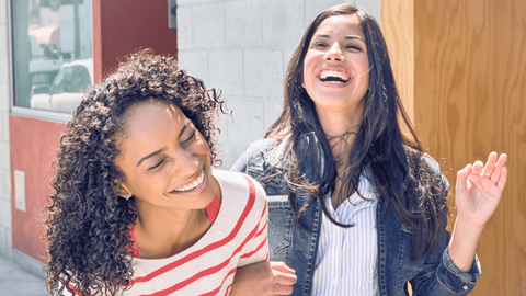 two young women laughing and smiling in front of a door